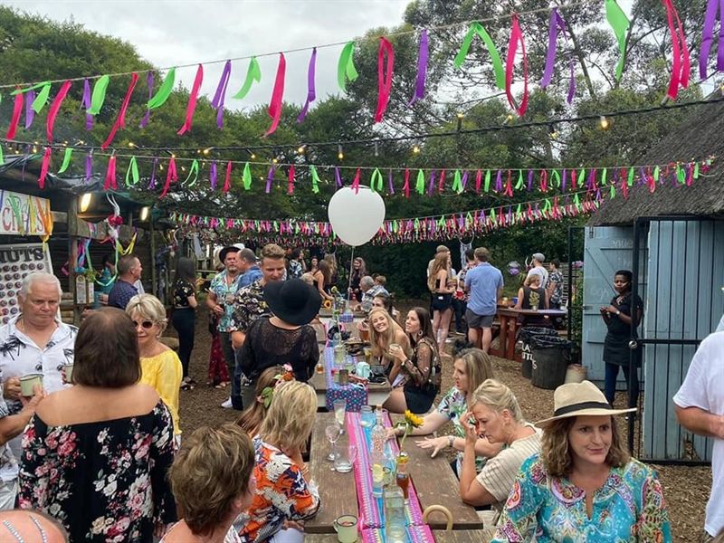 A Friday food fest: long tables of guests under bright ribbon bunting strung between the trees.